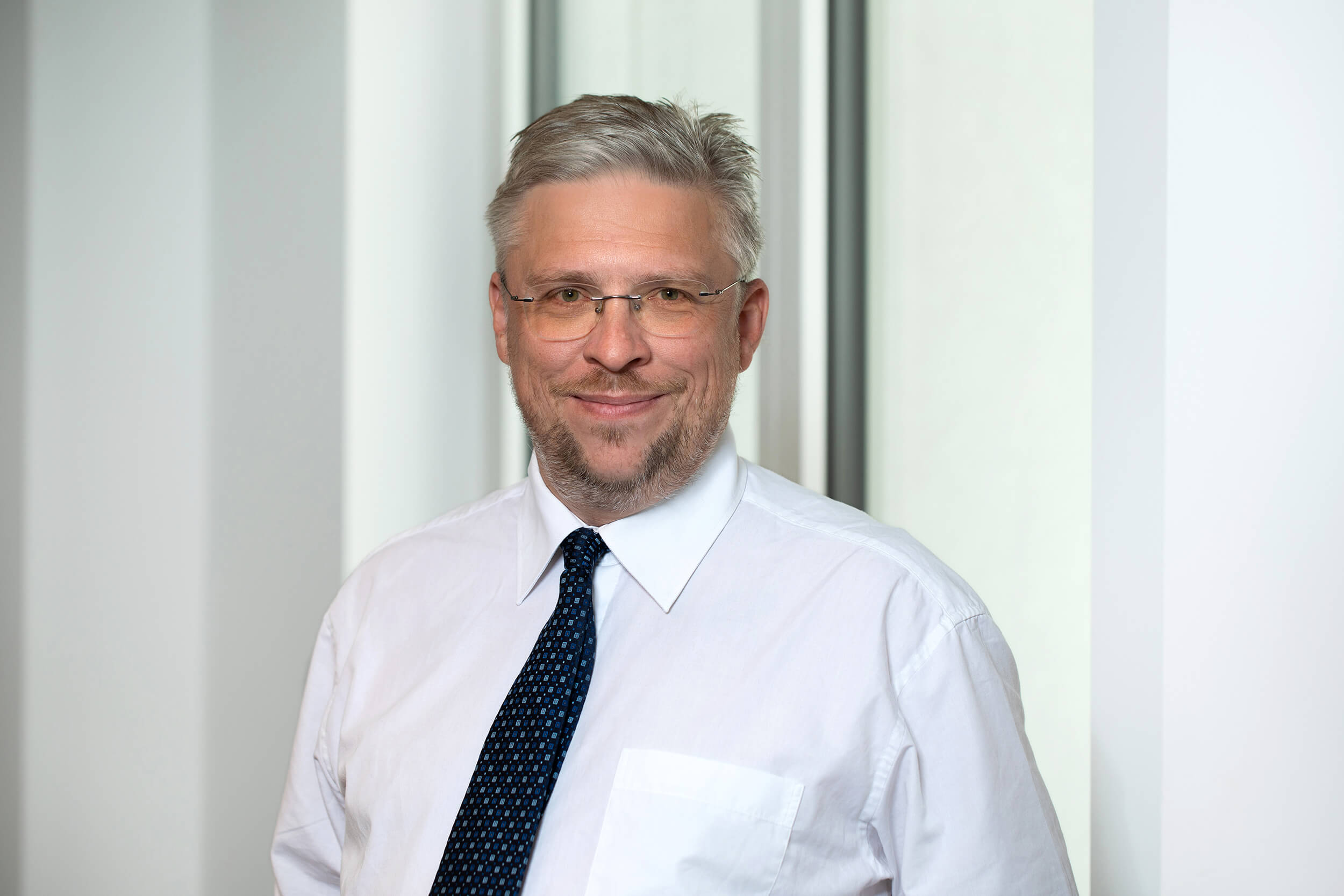 Portraitfoto von Christian Schnurrer vor neutralem Hintergrund.
